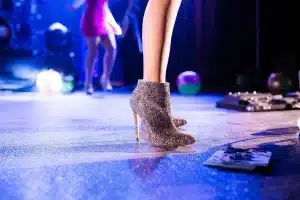 Performer su palco di teatro illuminato da riflettore con costumi e specchi di trucco