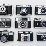 Mani che tengono una vecchia fotografia su un tavolo di legno con una fotocamera sfuocata