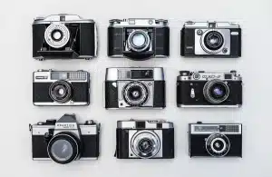 Mani che tengono una vecchia fotografia su un tavolo di legno con una fotocamera sfuocata