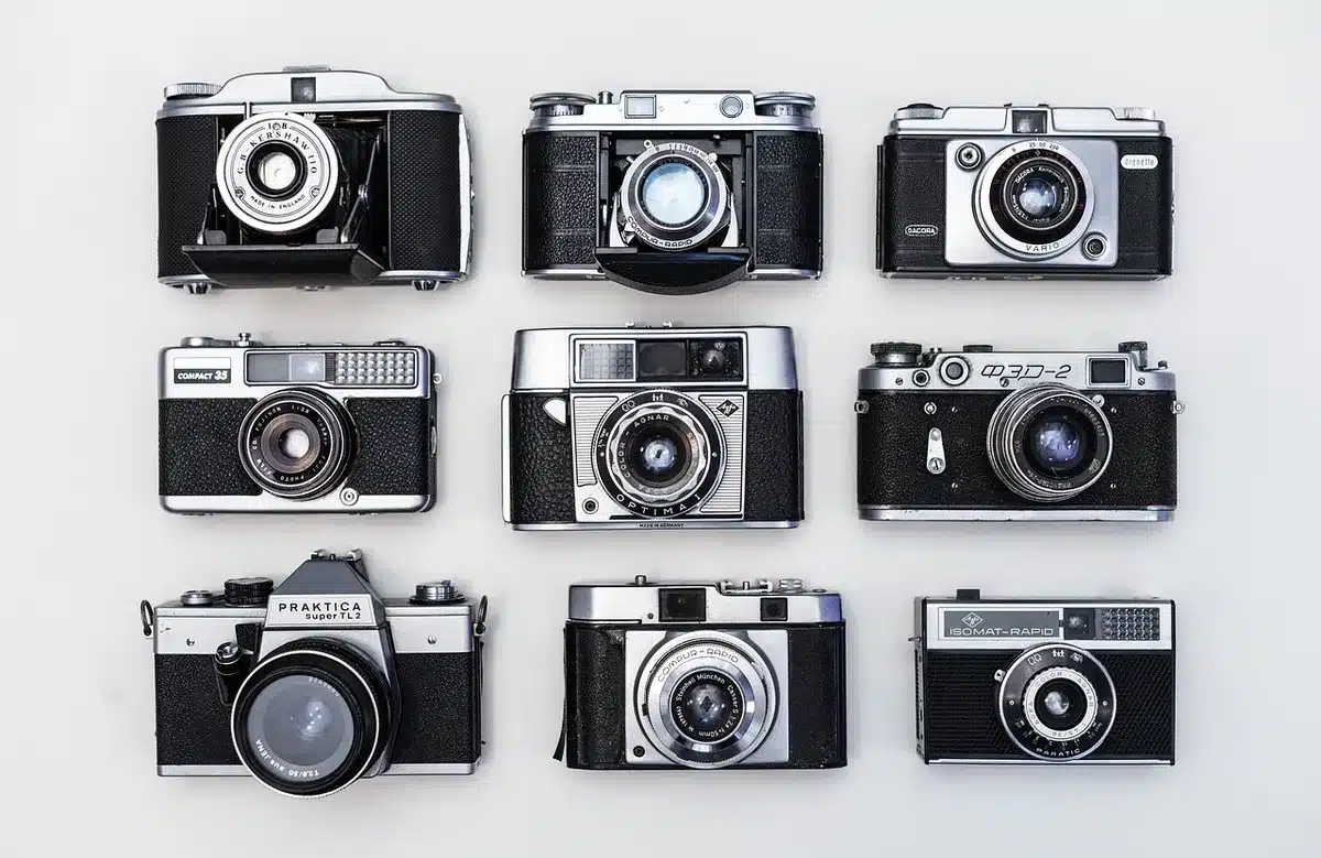 Mani che tengono una vecchia fotografia su un tavolo di legno con una fotocamera sfuocata