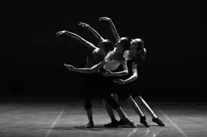 Sagome di ballerini e mani unite in uno studio di danza con luci di scena sfocate