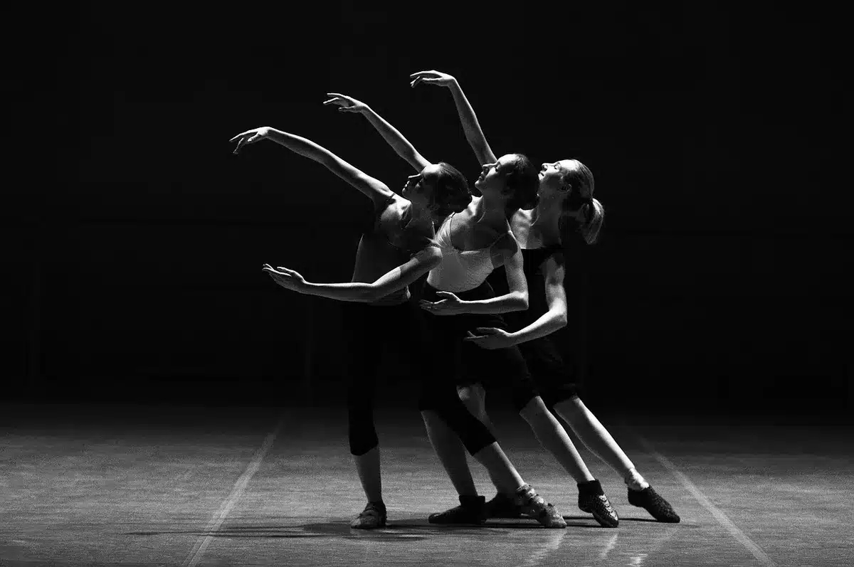 Sagome di ballerini e mani unite in uno studio di danza con luci di scena sfocate