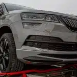 Fila di SUV anonimi parcheggiati davanti a una concessionaria, persone non identificabili sullo sfondo