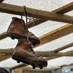 Mani che tengono uno stivale in pelle di montone e un campione di cuoio su un tavolo di legno