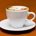 Macchina da scrivere vintage, libro e tazza su tavolo illuminato al mattino