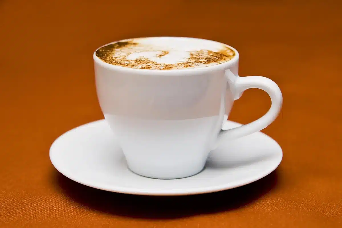Macchina da scrivere vintage, libro e tazza su tavolo illuminato al mattino