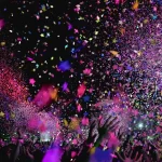 Pubblico anonimo con mani alzate davanti a un palco illuminato alla Hacienda