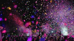 Pubblico anonimo con mani alzate davanti a un palco illuminato alla Hacienda