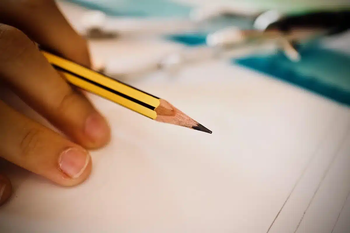 Primo piano di una mano che disegna con matita su carta, linee visibili