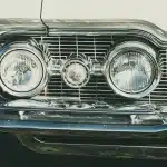 Linee di auto anonime in un capannone, evidenza su fari e pannelli per differenziazione
