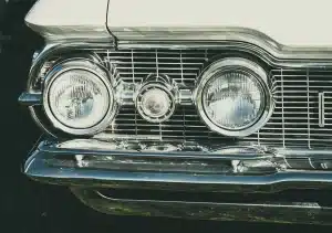 Linee di auto anonime in un capannone, evidenza su fari e pannelli per differenziazione