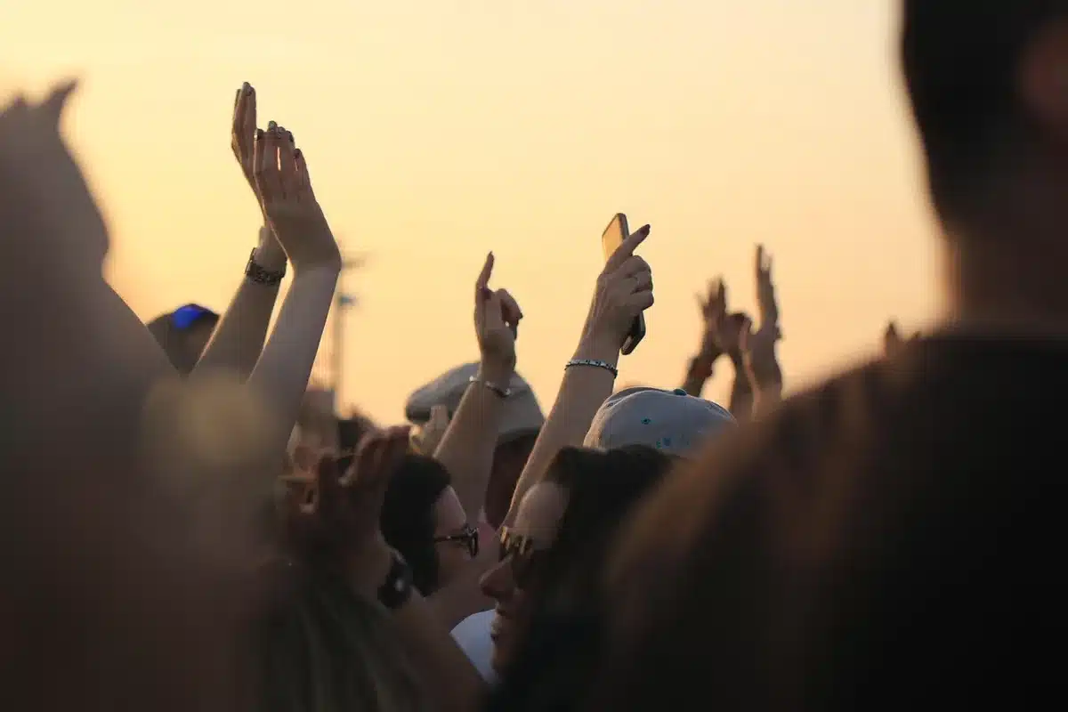 Persone con magliette da festival e badge sulla spiaggia, folla diretta verso il mare