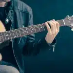 Chitarra acustica, cuffie e taccuino su un tavolo in una piccola sala prove
