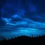Silhouette di persone attorno a un tavolo con luci soffuse, atmosfera di tensione