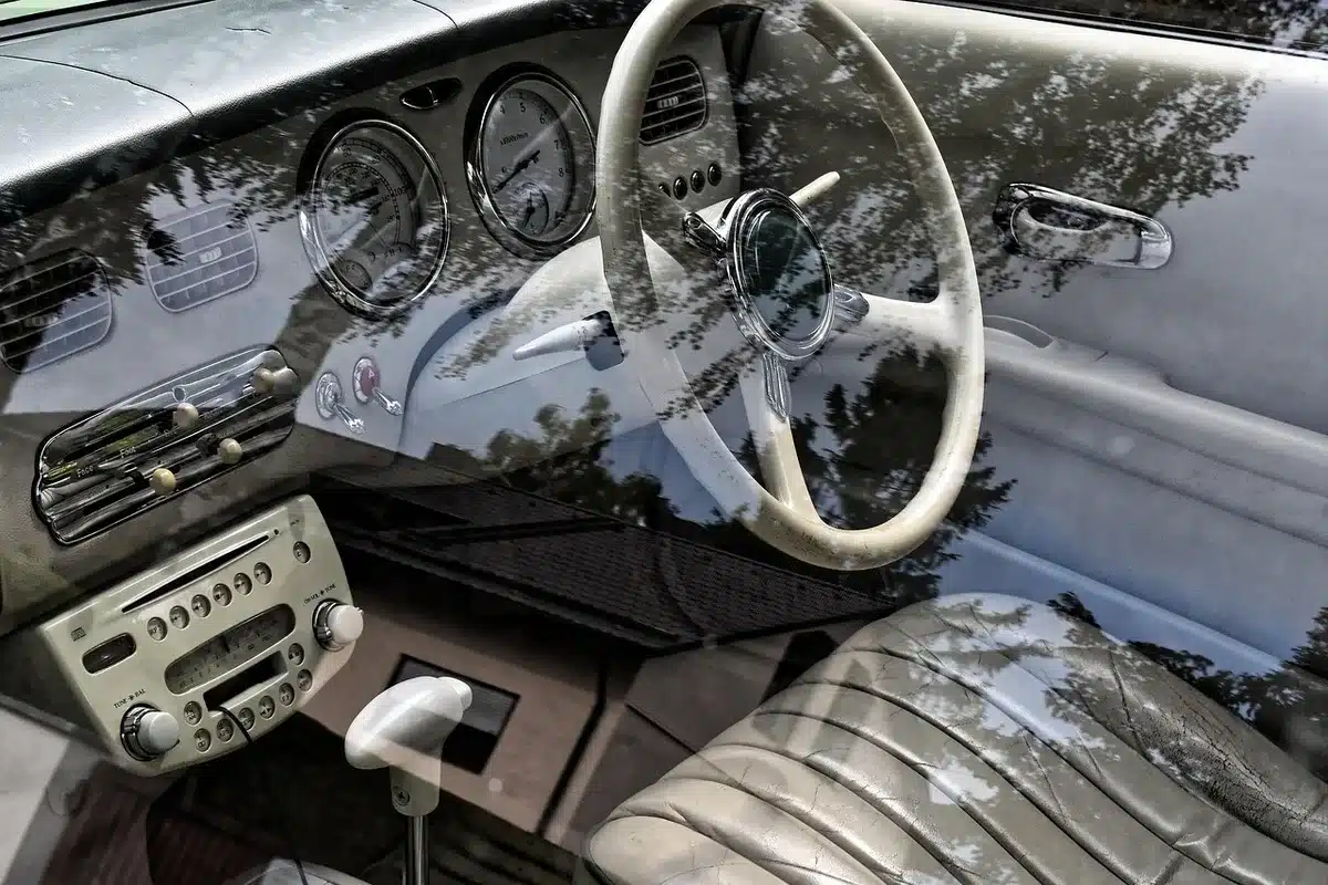 Interno di un'auto visto dal parabrezza con mani sul volante