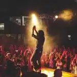 Pubblico che applaude una band in controluce sul palco