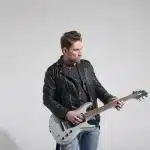 Scrivania con schizzi punk, matite e chitarra in uno studio domestico