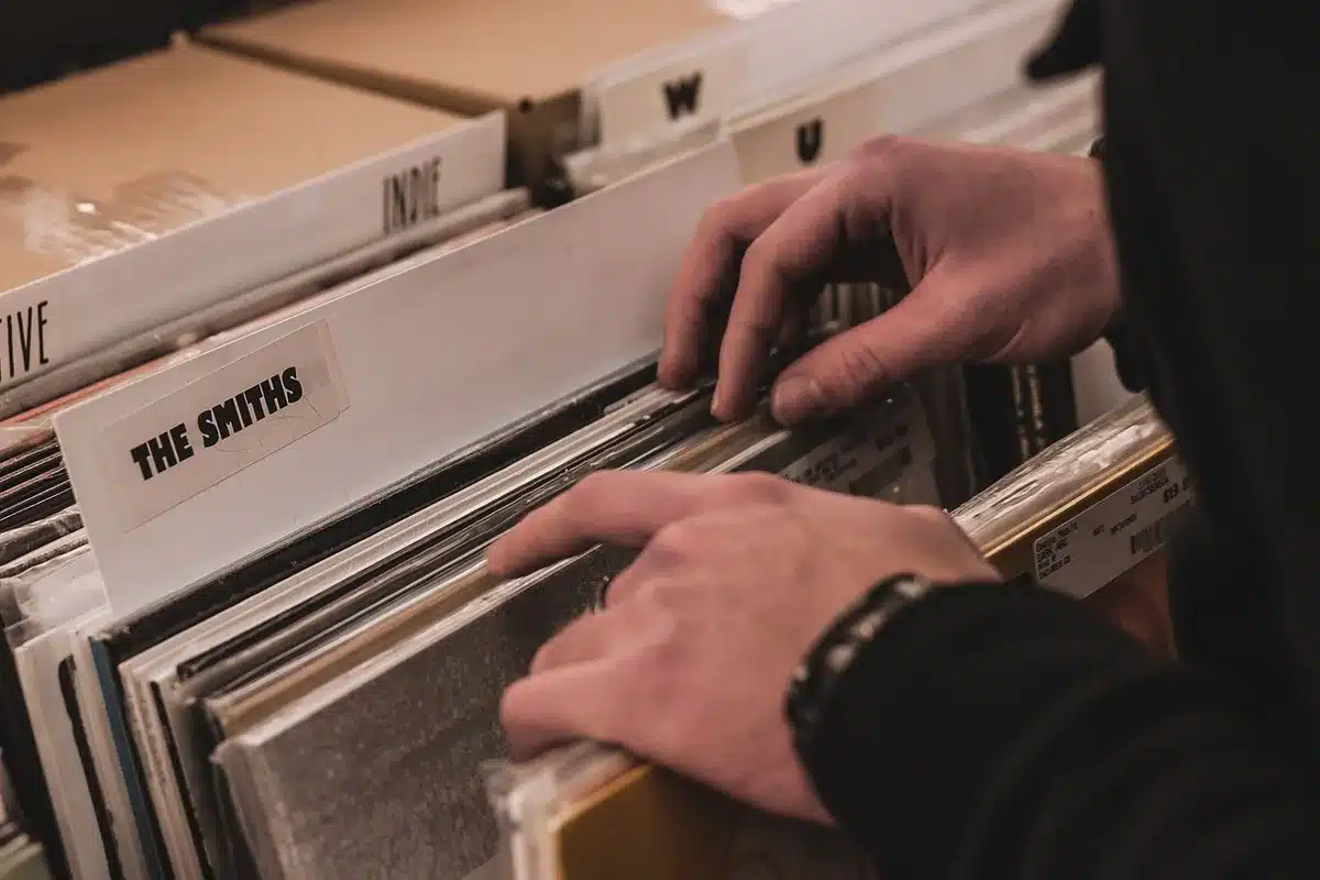 Vinile 180 g parzialmente estratto dalla sua copertina, mani che lo maneggiano su un tavolo